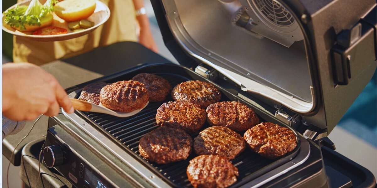 A ninja Woodfire electric BBQ with burgers cooking on it