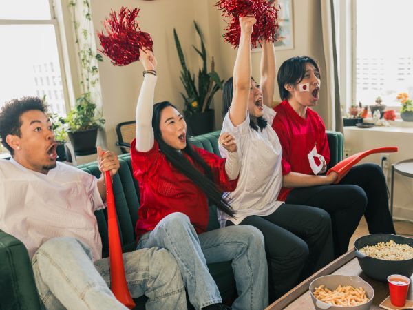 Sports fans watching TV at home sitting on a sofa.