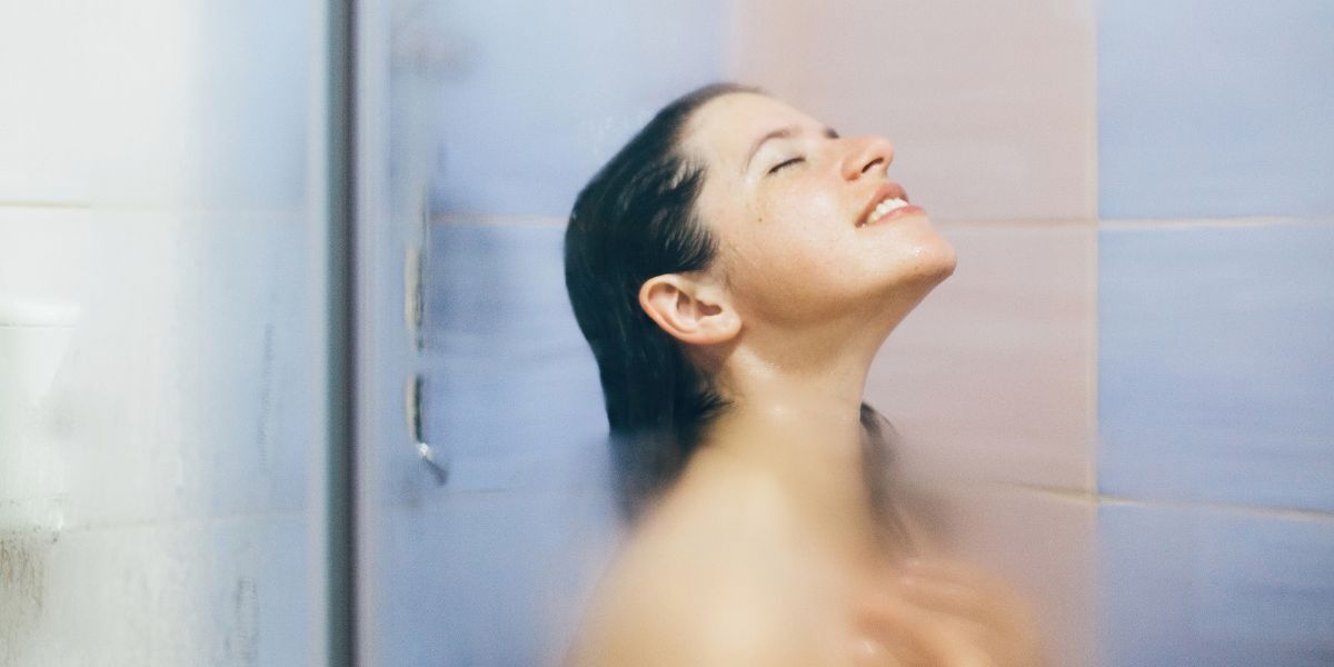 A smiling woman enjoys a hot shower