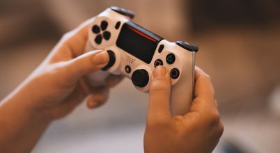 Hands holding a PS4 gaming controller
